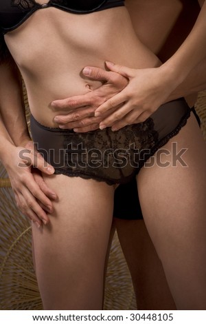 Torso of unrecognizable male and female. Woman in lingerie. Man hands hugging her stomach and hips area from behind