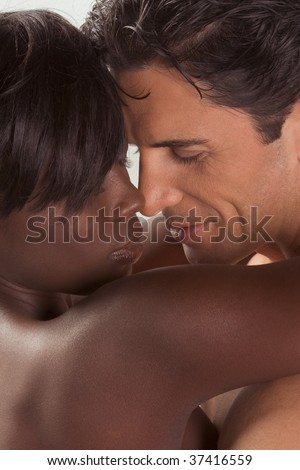 Loving affectionate nude heterosexual couple in sensual kiss and hug. Mid adult Caucasian men in late 30s and young black African-American woman in 20s