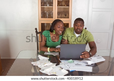 Financial adviser helping organize and optimize home finances bills, Young black African American couple sitting table with pc laptop computer and trying to work through pile of bills to pay on-line