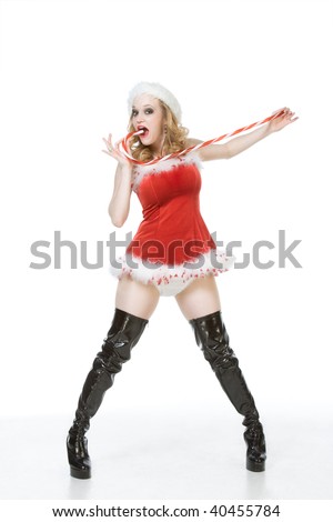 Blond excited pinup dancing woman in Christmas outfit and thigh high black leather boots holding huge candy cane stick