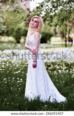 Beautiful young bride in white dress in summer green park