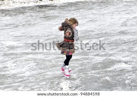 little girl learning ice skating outdoors