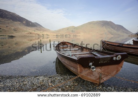 Boats sitting by the lake in a peaceful scene taken at Crummock Water near Buttermere in the English Lake District, Cumbria, England.