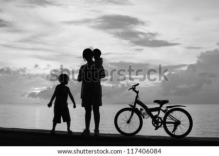 Biker family silhouette  at the beach at sunset.