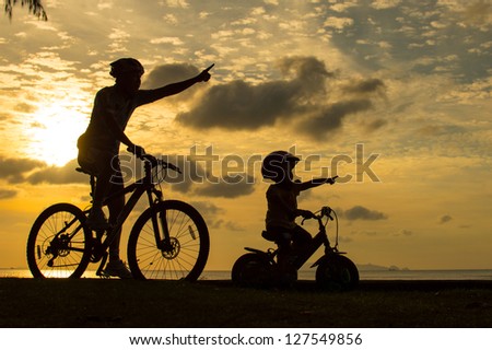Biker family silhouette on the beach at sunset.