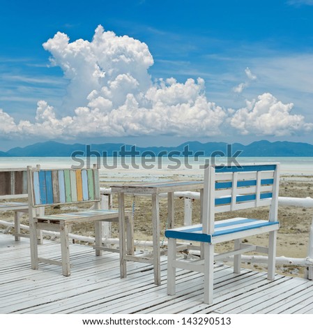 Old style wood chairs and table with ocean background.
