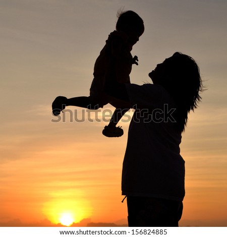 silhouette of mother and small girl on the beach at dusk.