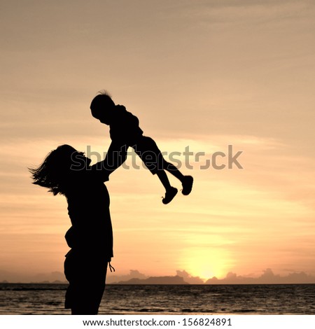 silhouette of mother and small girl on the beach at dusk.