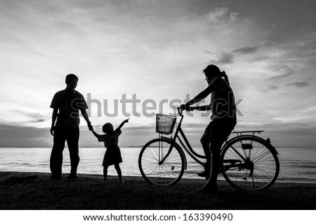 Silhouette of a biker family on the beach at dusk.