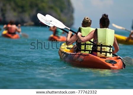 traveler kayaking in the thai ocean from backward view