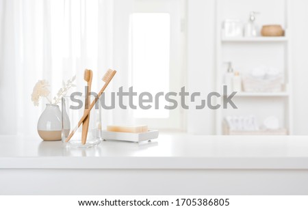 Table with toothbrushes and soap inside a bright defocused bathroom