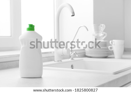 Dishwashing liquid bottle on kitchen sink and clean plates background