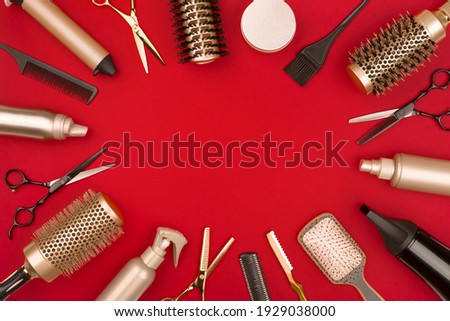 Hair cutting tools arranged in a circle on red background