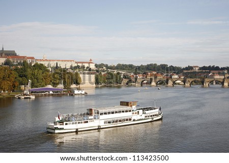 Tour Boat passing vltava river, Prague Castle and Charles Bridge in the distance