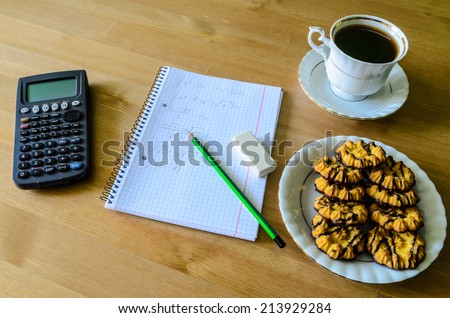 workplace, study place with calculator, workbook, cup of coffee and cookies - stock photo
