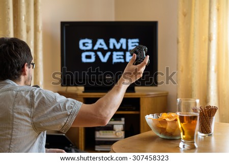 man playing video games (on television) and losing - game over - stock photo