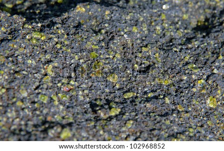 Green sand crystals of Olivine are adhered to rocks on the Green Sand Beach of the Big Island of Hawaii.