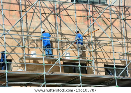 Two men stand on scaffolding and work on exterior repairs on the City Building in downtown, Asheville, North Carolina.
