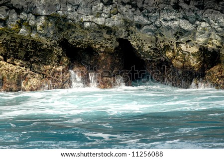 Water spills out of crevices of Kilhauea Point National Wildlife Refuge of Kauai, Hawaii.  Rocky cliffs and aqua blue water.
