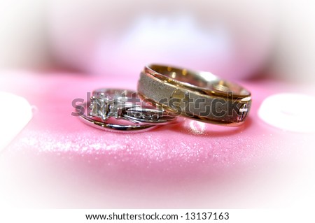 Antique gold wedding band sits on top of bride\'s wedding rings.  Hot pink wedding cake icing.  Bride is dreaming of her special day.