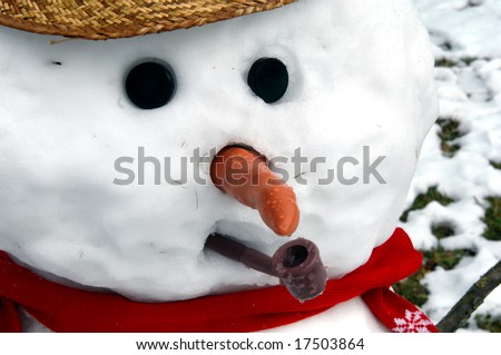 Cold face of snowman has carrot nose, pipe and button eyes.  Red scarf and straw hat.