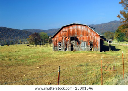 Barn and field with fence row.  Blue skies and Ozark Mountains in background.  Cattle grazing.