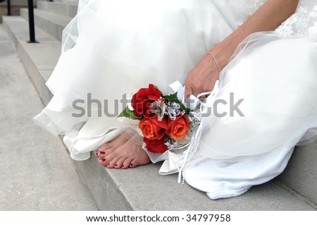 Bride is barefoot on the church steps her feet aching, she lays her bouquet of red and orange roses besides them.
