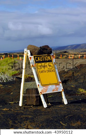 Sign is secured with lava rocks.  White folding sign with yellow caution sign attached stating \