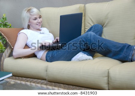 attractive young woman sitting on a couch with laptop computer