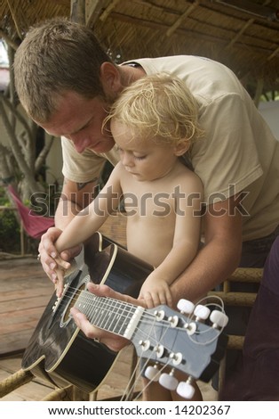 young boy is getting guitar lessons from his father