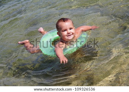 portrait of happy baby swimming in swim trainer