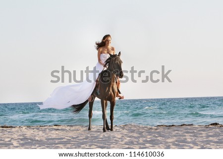 young beautiful woman in white dress riding horse on sea background