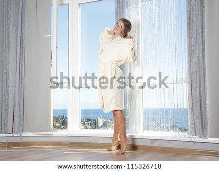 young happy woman enjoying sea view in hotel / room next to big window