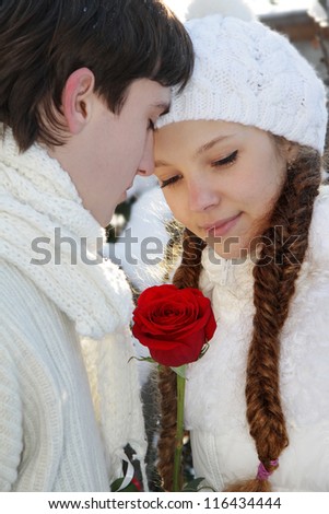 young loving couple with red rose on natural winter background
