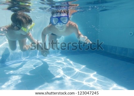 two children diving in masks underwater in pool