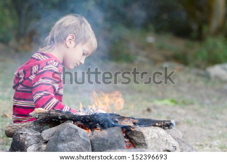 outdoor portrait of young child boy looking at fire