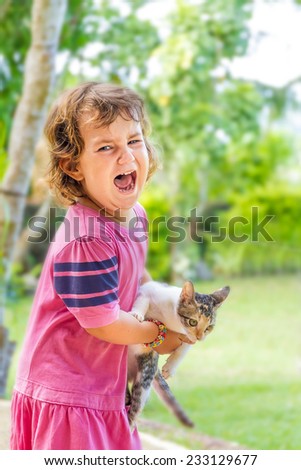 outdoor portrait of young child girl with small kitten, girl playing with cat on natural background