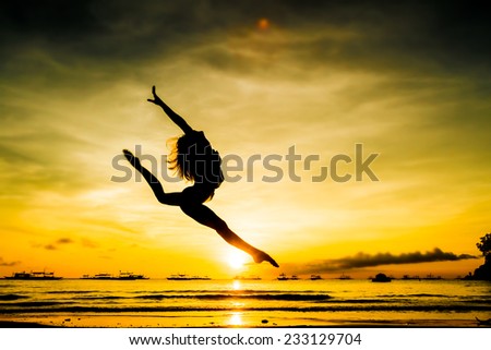 silhouette of jumping girl on tropical sunset sea and sky background