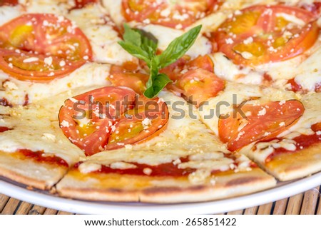 freshly baked pizza with cheese and tomatoes served in small outdoor restaurant, meal time