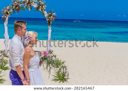 bride and groom enjoying beach wedding in tropics, on wedding arch, setup background