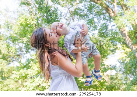 happy young mother with child - baby boy - outdoor portrait on green natural background