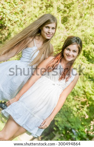 two young happy girls on natural green background, smiling happy girls outdoor portrait
