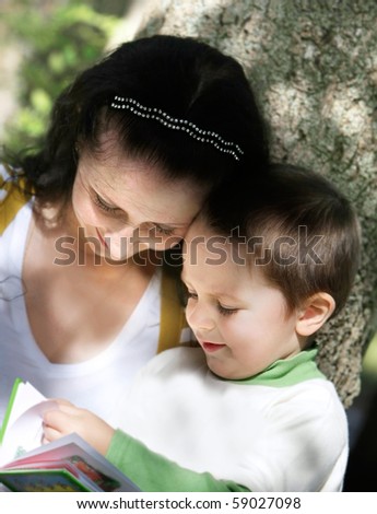 mother and son reading book outdoors