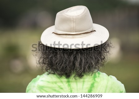 Back of a man\'s head who is wearing a hat and has long graying hair