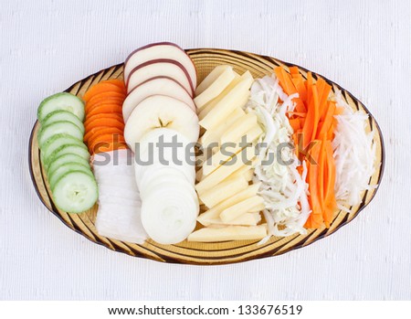 Sliced vegetables display on glass dish on white cloth background