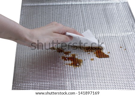 housewife\'s hand cleaning stained soy bean sauce on foil sheet
