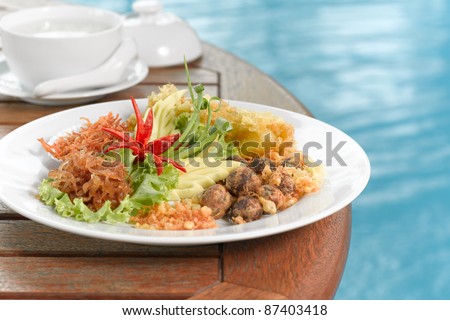 An ancient thai food, rice in cold water or ice served with fried sweet pork, fried shrimp paste,fried egg and vegetable known as \