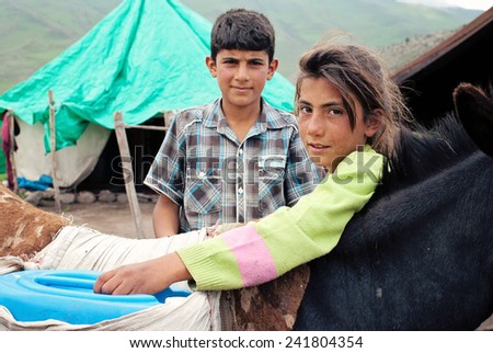 ARRARAT, TURKEY - Unidentified bedouin girl grabs a water canister when unloading her donkey. These poor families live in foothills of Arrarat circa July 2011.