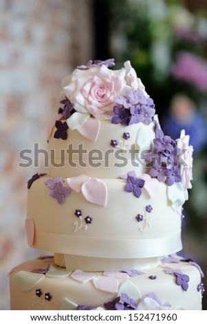 Closeup of wedding cake detail showing ornate pink and purple flower decoration