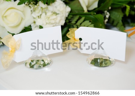 Closeup detail of wedding reception place cards on top table with white floral arrangement
